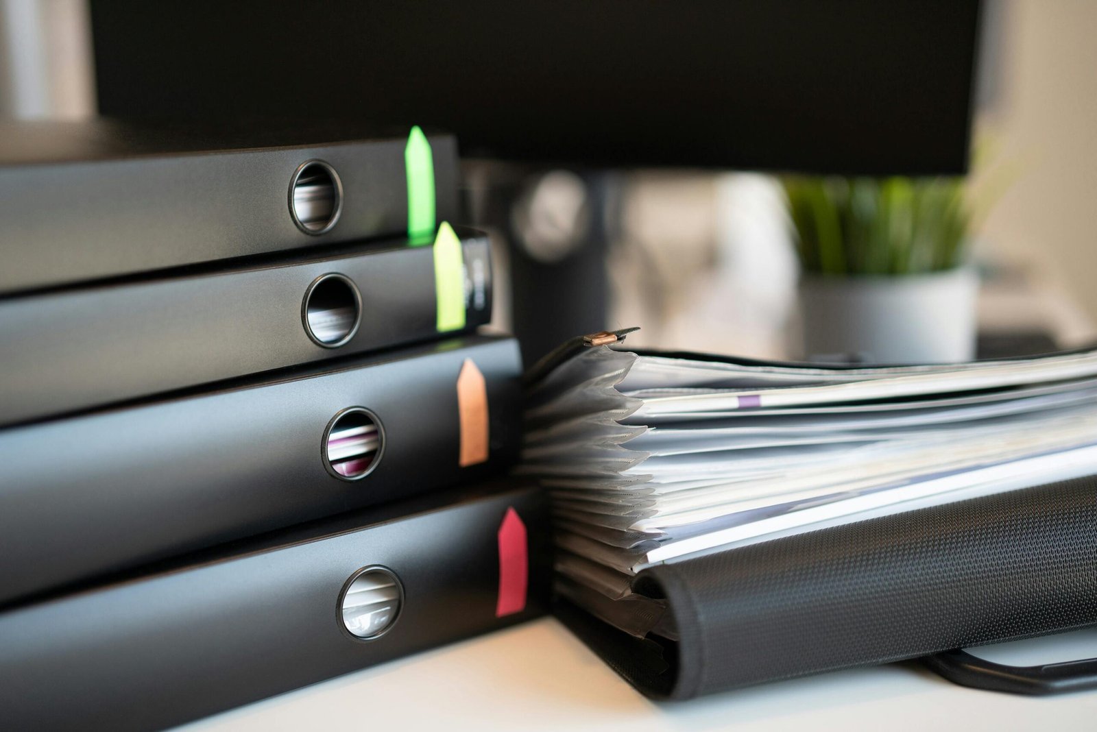 society statutory compliances Stack of colorful ring binders and documents on a modern office desk setting.